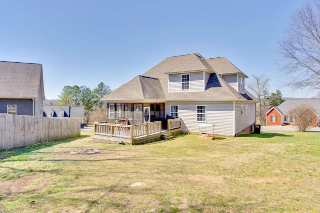 rear view of property with a lawn, fence, roof with shingles, and a wooden deck