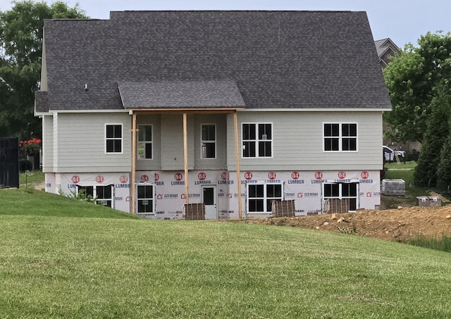 rear view of house with a yard and a shingled roof