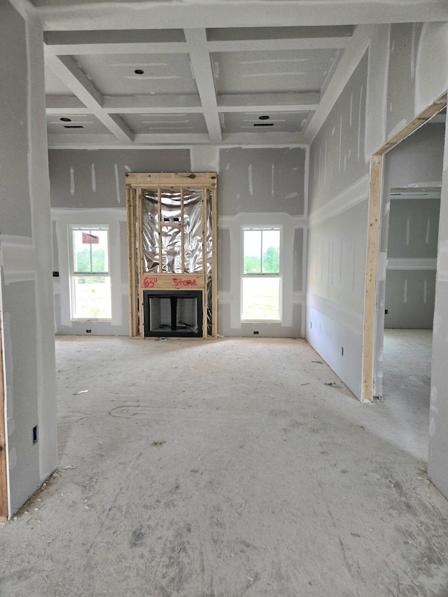 unfurnished living room with a healthy amount of sunlight, beamed ceiling, a fireplace, and coffered ceiling