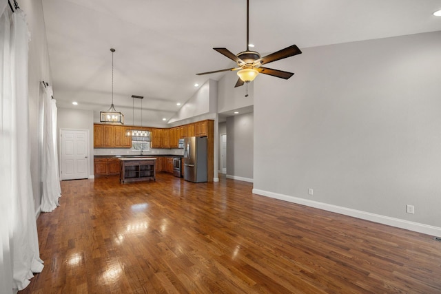 unfurnished living room with high vaulted ceiling, a ceiling fan, baseboards, and dark wood-style flooring