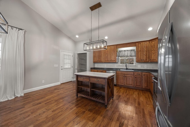 kitchen with brown cabinetry, appliances with stainless steel finishes, lofted ceiling, and a sink