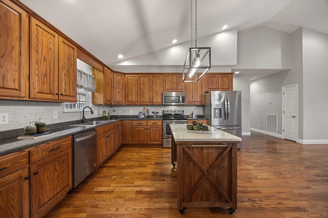 kitchen featuring visible vents, brown cabinets, dark wood-style floors, stainless steel appliances, and a sink