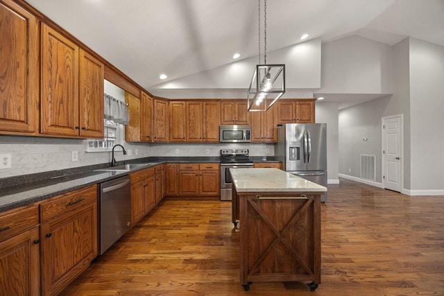 kitchen with visible vents, dark wood-type flooring, brown cabinets, stainless steel appliances, and a sink