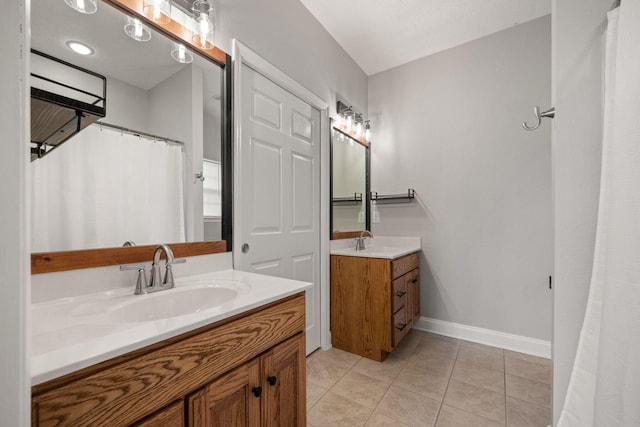 full bathroom featuring tile patterned flooring, two vanities, baseboards, and a sink