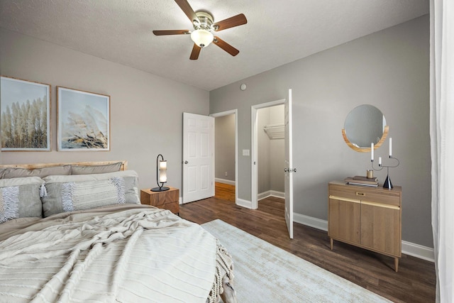 bedroom featuring ceiling fan, baseboards, a textured ceiling, and dark wood finished floors