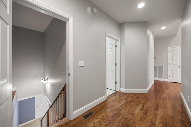 hall with visible vents, baseboards, and wood finished floors