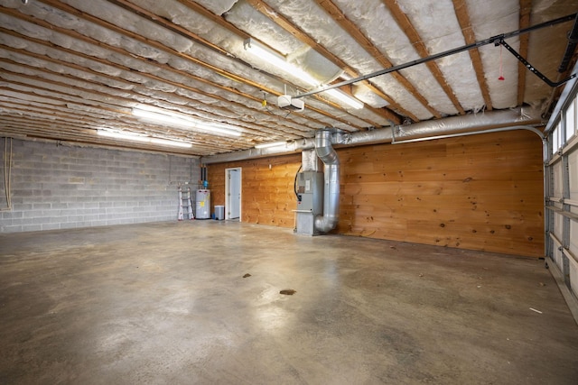 garage with heating unit, concrete block wall, and water heater