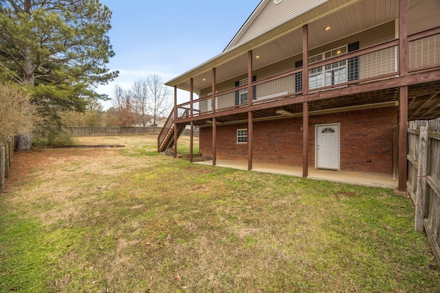 back of property with brick siding, fence, stairs, a lawn, and a patio area