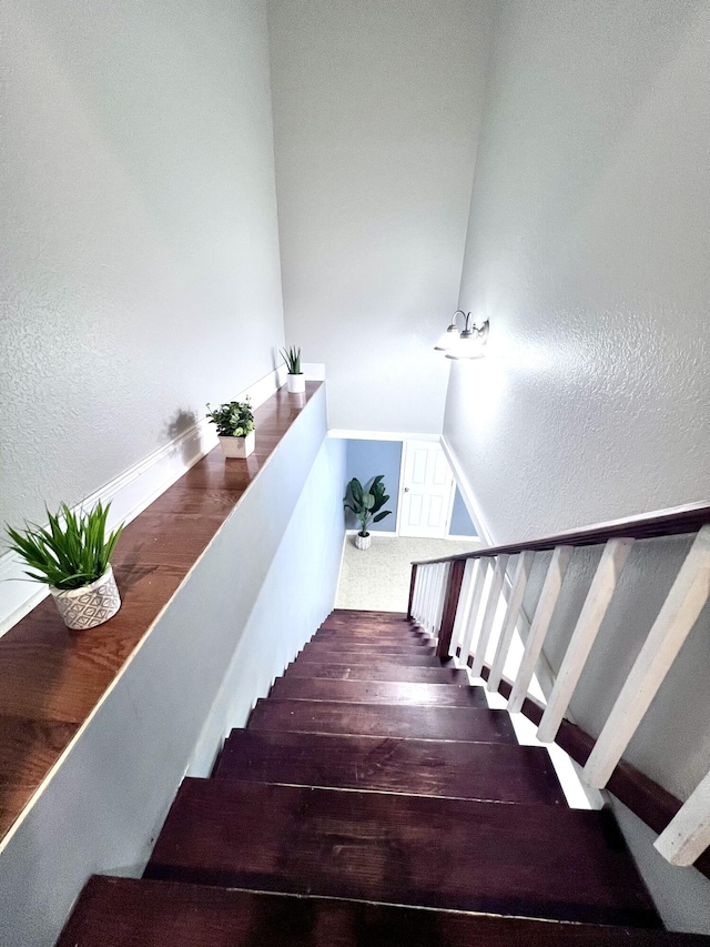 staircase featuring a textured wall and wood finished floors