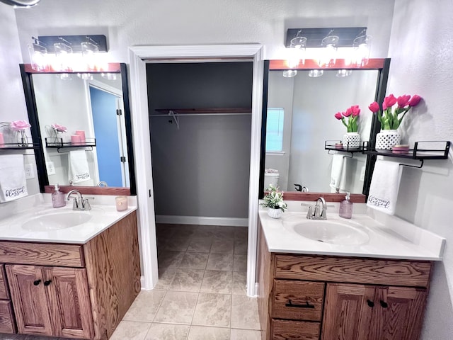 full bathroom featuring tile patterned floors, two vanities, baseboards, and a sink