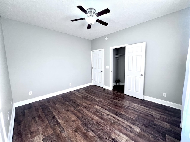 unfurnished bedroom featuring baseboards, dark wood-style flooring, ceiling fan, a closet, and a textured ceiling