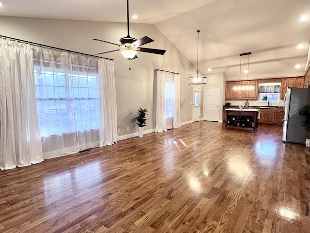 unfurnished living room featuring dark wood-style floors, high vaulted ceiling, a ceiling fan, and baseboards