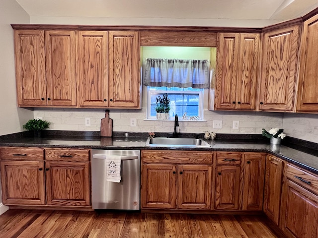 kitchen with dark countertops, a sink, brown cabinets, and stainless steel dishwasher