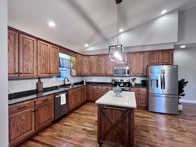 kitchen featuring a sink, lofted ceiling, wood finished floors, and stainless steel appliances