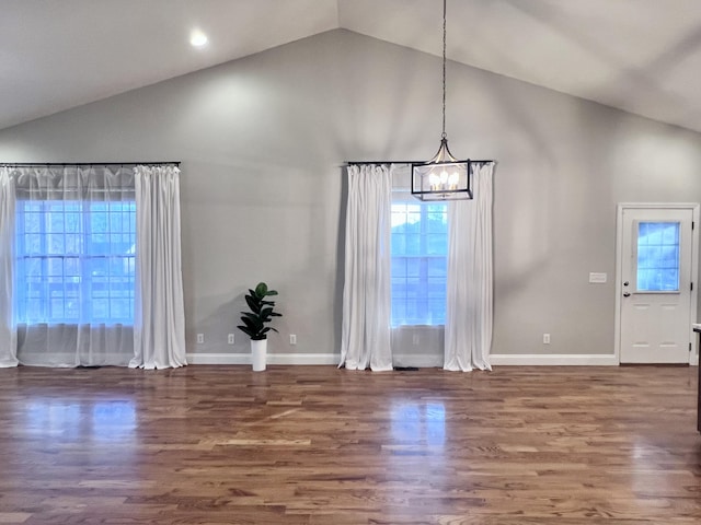 unfurnished dining area with an inviting chandelier, wood finished floors, baseboards, and high vaulted ceiling