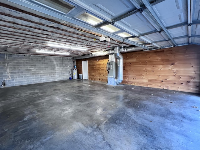 garage with heating unit, concrete block wall, a garage door opener, and water heater