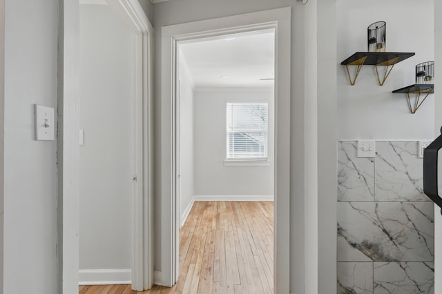 hall with baseboards, light wood-style floors, and ornamental molding