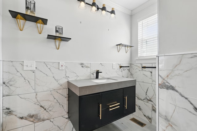 bathroom featuring visible vents, tile walls, wainscoting, crown molding, and vanity