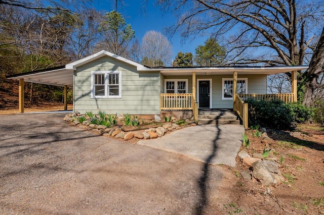 ranch-style home with aphalt driveway, an attached carport, and a porch