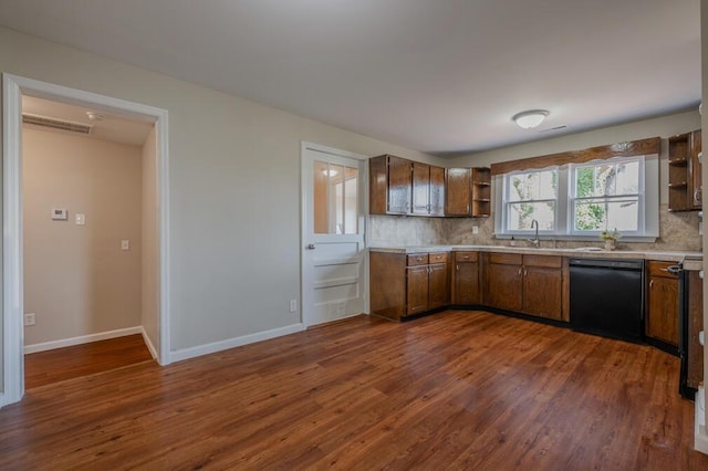 kitchen featuring open shelves, dark wood finished floors, black dishwasher, decorative backsplash, and a sink