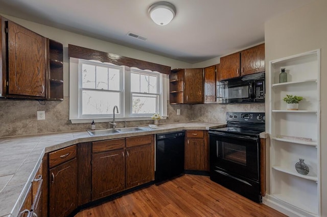 kitchen featuring visible vents, open shelves, a sink, tile counters, and black appliances