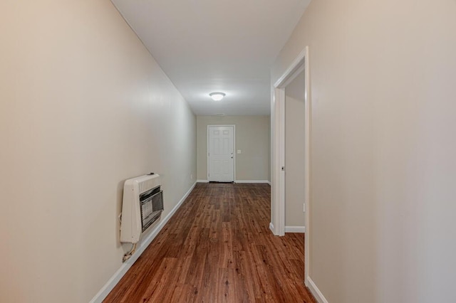 hall featuring heating unit, baseboards, and dark wood-style flooring