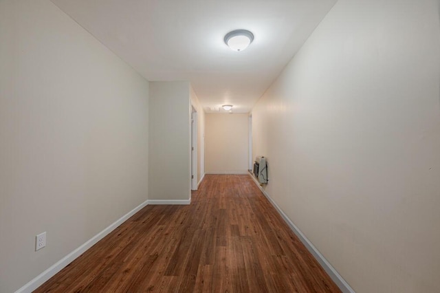 hall featuring heating unit, wood finished floors, and baseboards