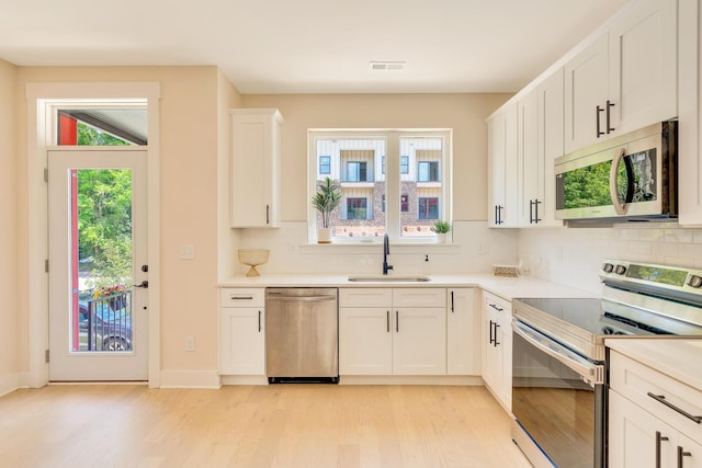 kitchen with plenty of natural light, backsplash, stainless steel appliances, and a sink