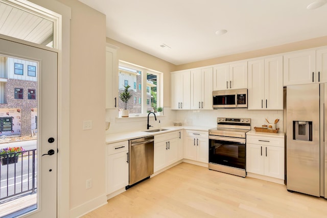 kitchen featuring a sink, stainless steel appliances, light wood-style floors, light countertops, and decorative backsplash