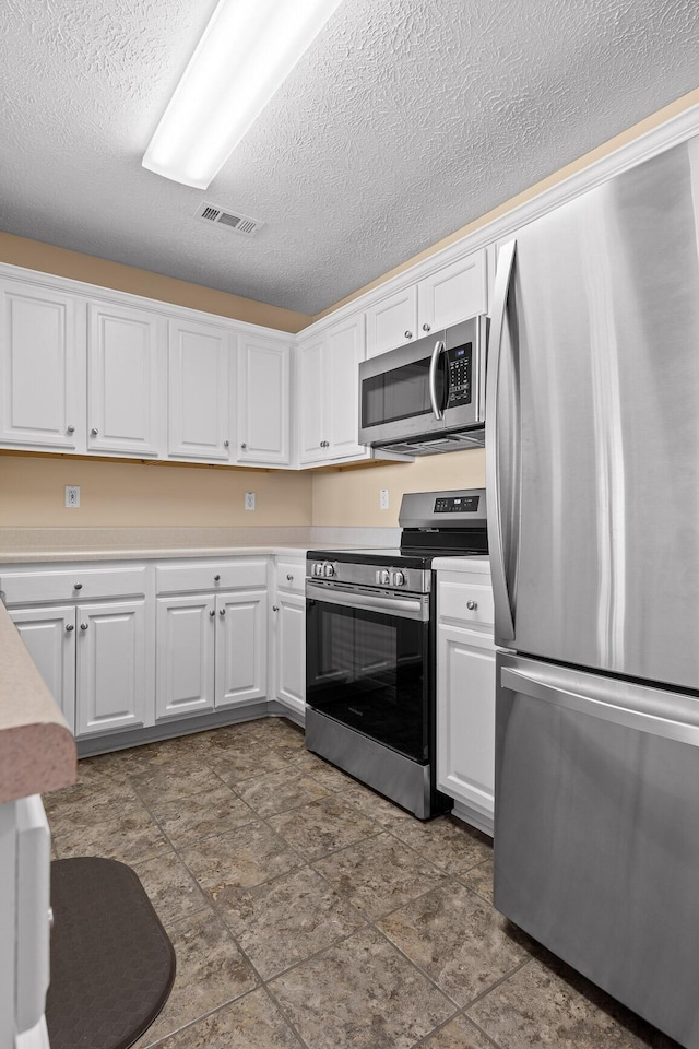 kitchen featuring visible vents, stainless steel appliances, light countertops, a textured ceiling, and white cabinetry