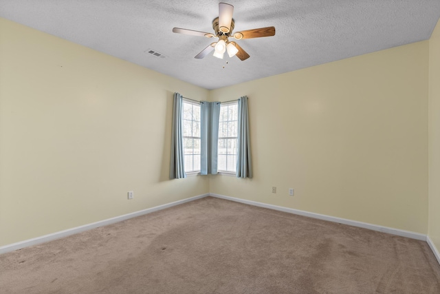 carpeted empty room featuring baseboards, a ceiling fan, visible vents, and a textured ceiling