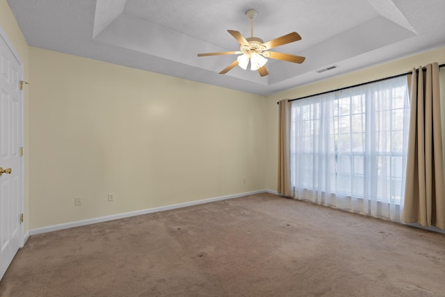 carpeted empty room featuring visible vents, baseboards, a textured ceiling, a raised ceiling, and a ceiling fan