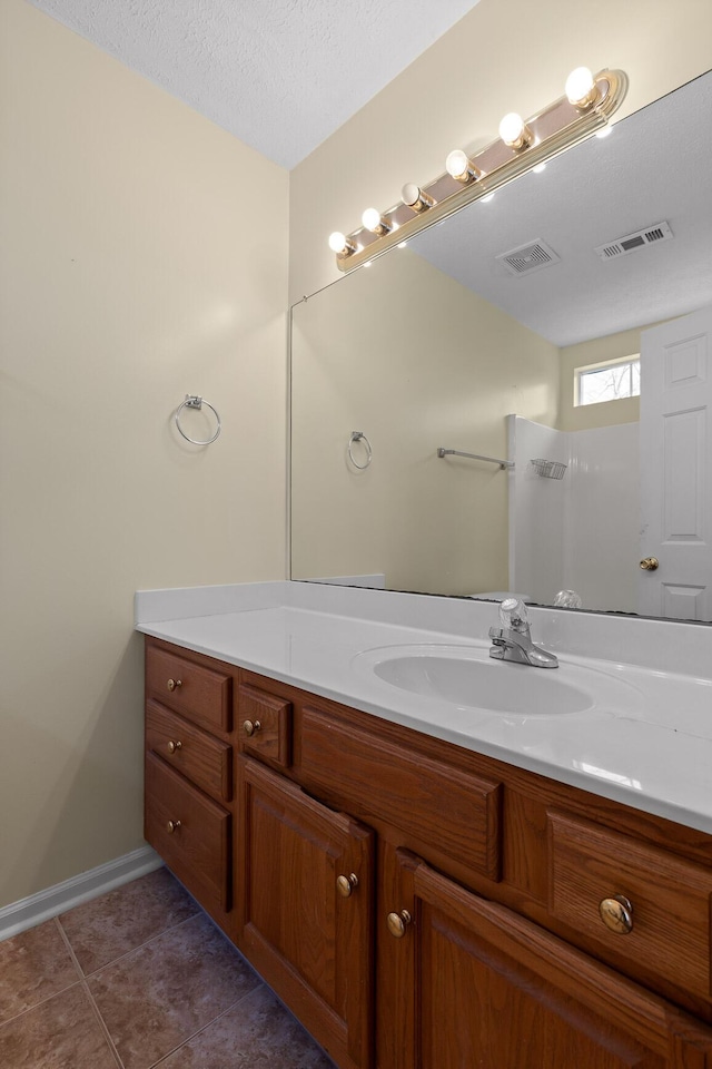 bathroom with visible vents, a textured ceiling, vanity, and tile patterned flooring