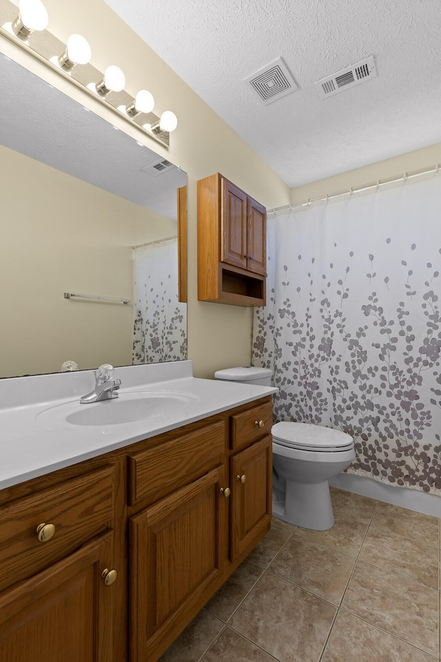 bathroom featuring visible vents, toilet, vanity, and a textured ceiling