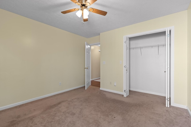 unfurnished bedroom featuring baseboards, carpet, a closet, a textured ceiling, and a ceiling fan