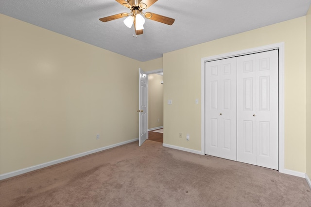 unfurnished bedroom with a textured ceiling, a closet, carpet floors, baseboards, and ceiling fan