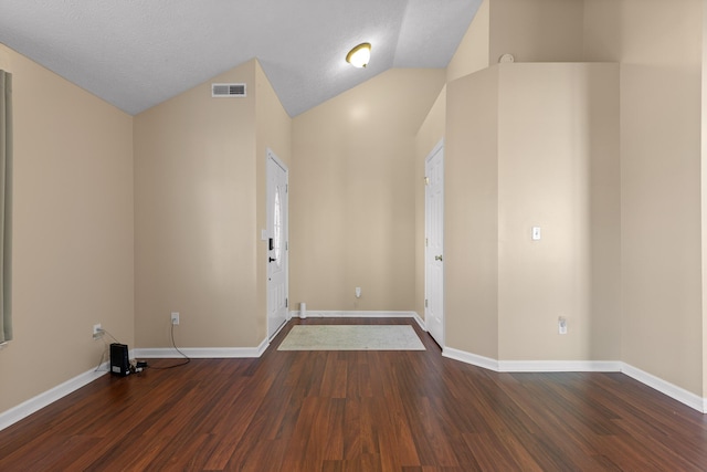 foyer entrance featuring vaulted ceiling, wood finished floors, visible vents, and baseboards