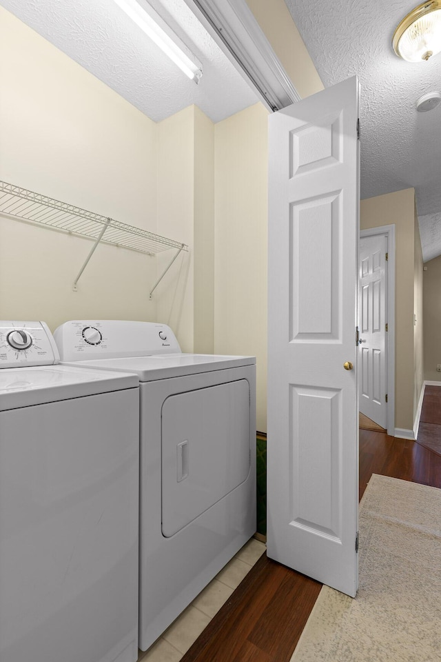 laundry room featuring laundry area, washer and dryer, a textured ceiling, and light wood-type flooring