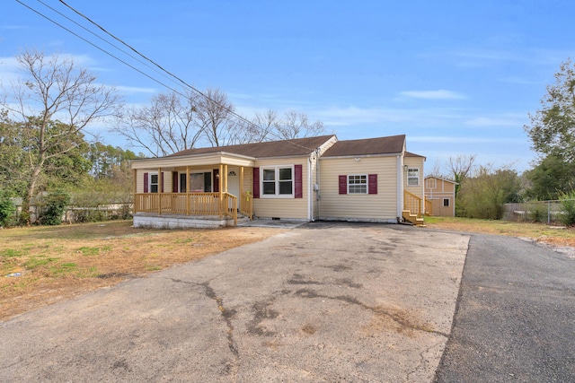 view of front of home featuring a porch, fence, and driveway