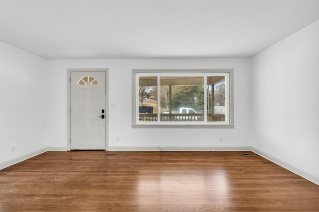 unfurnished room with visible vents, baseboards, and wood finished floors