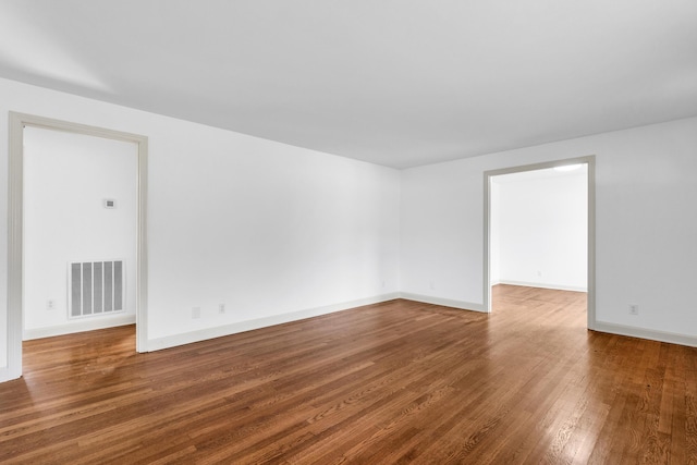 empty room with visible vents, wood-type flooring, and baseboards