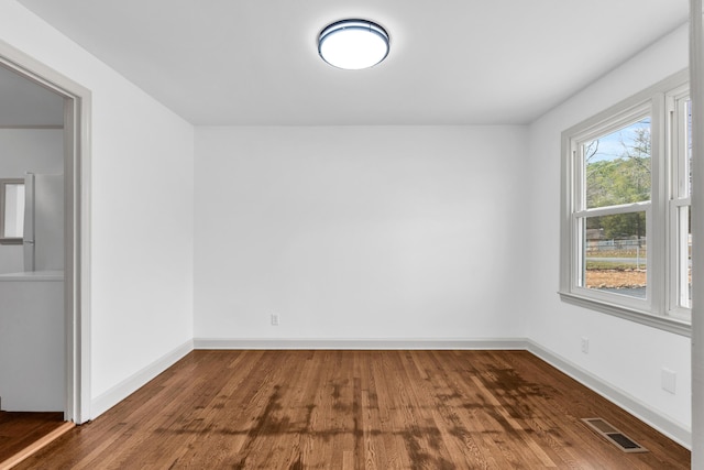 empty room with visible vents, baseboards, and wood finished floors