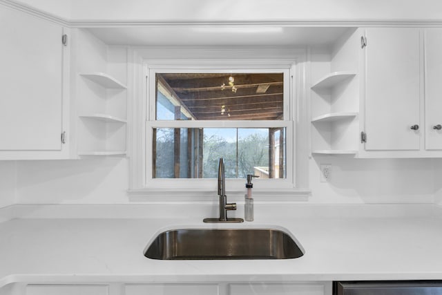 kitchen featuring a sink, white cabinets, light countertops, and open shelves