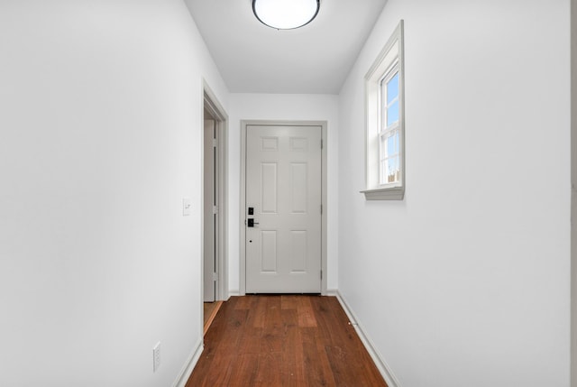 corridor with baseboards and dark wood-style flooring