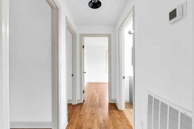 hallway with visible vents, baseboards, and light wood finished floors