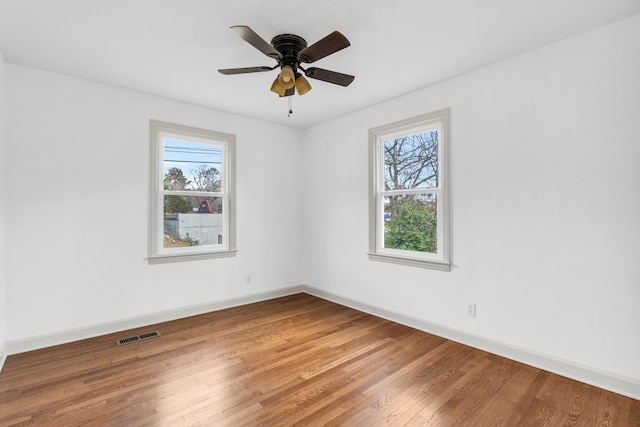 unfurnished room featuring a wealth of natural light, visible vents, baseboards, and light wood finished floors