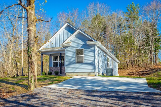 view of front facade featuring a front lawn, cooling unit, and board and batten siding