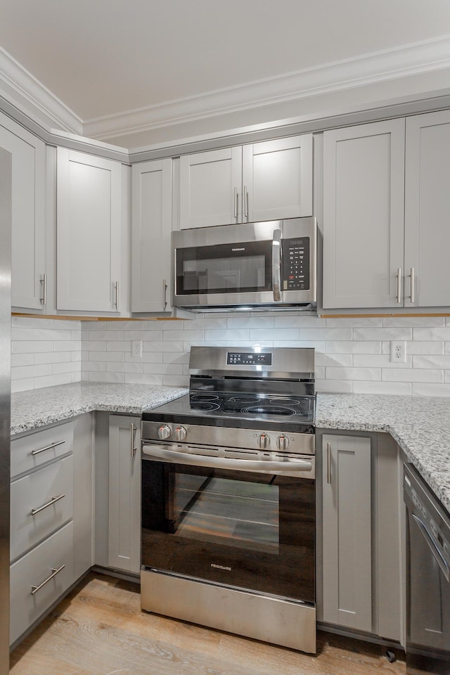 kitchen with decorative backsplash, gray cabinetry, stainless steel appliances, and ornamental molding