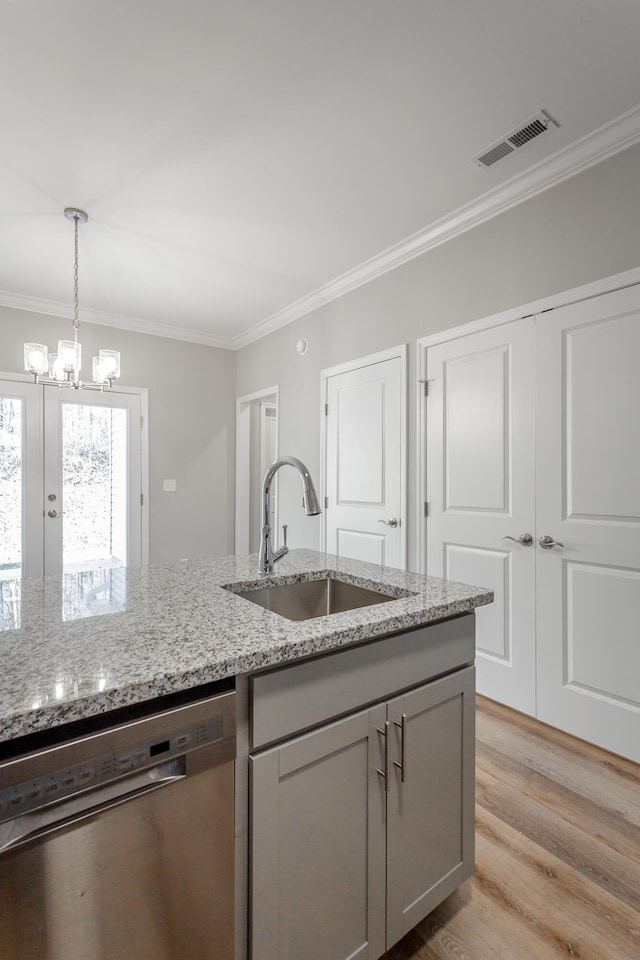 kitchen featuring visible vents, dishwasher, light wood-type flooring, ornamental molding, and a sink