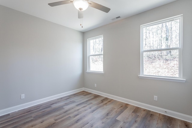 spare room featuring visible vents, baseboards, and wood finished floors